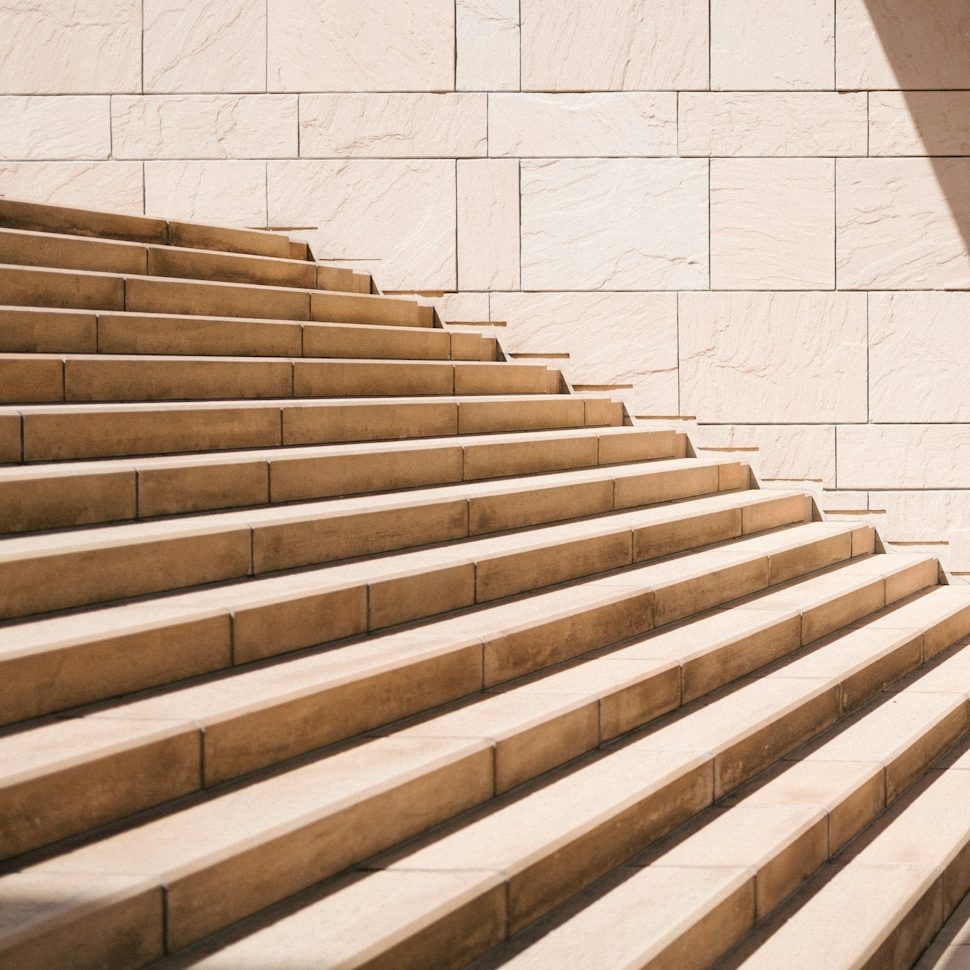 Holzverkleidete Treppe mit hellen, klaren Wänden im Hintergrund.